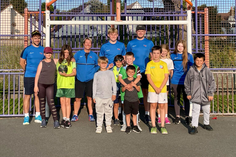 A group of young people smiling and posing together in a sports setting.